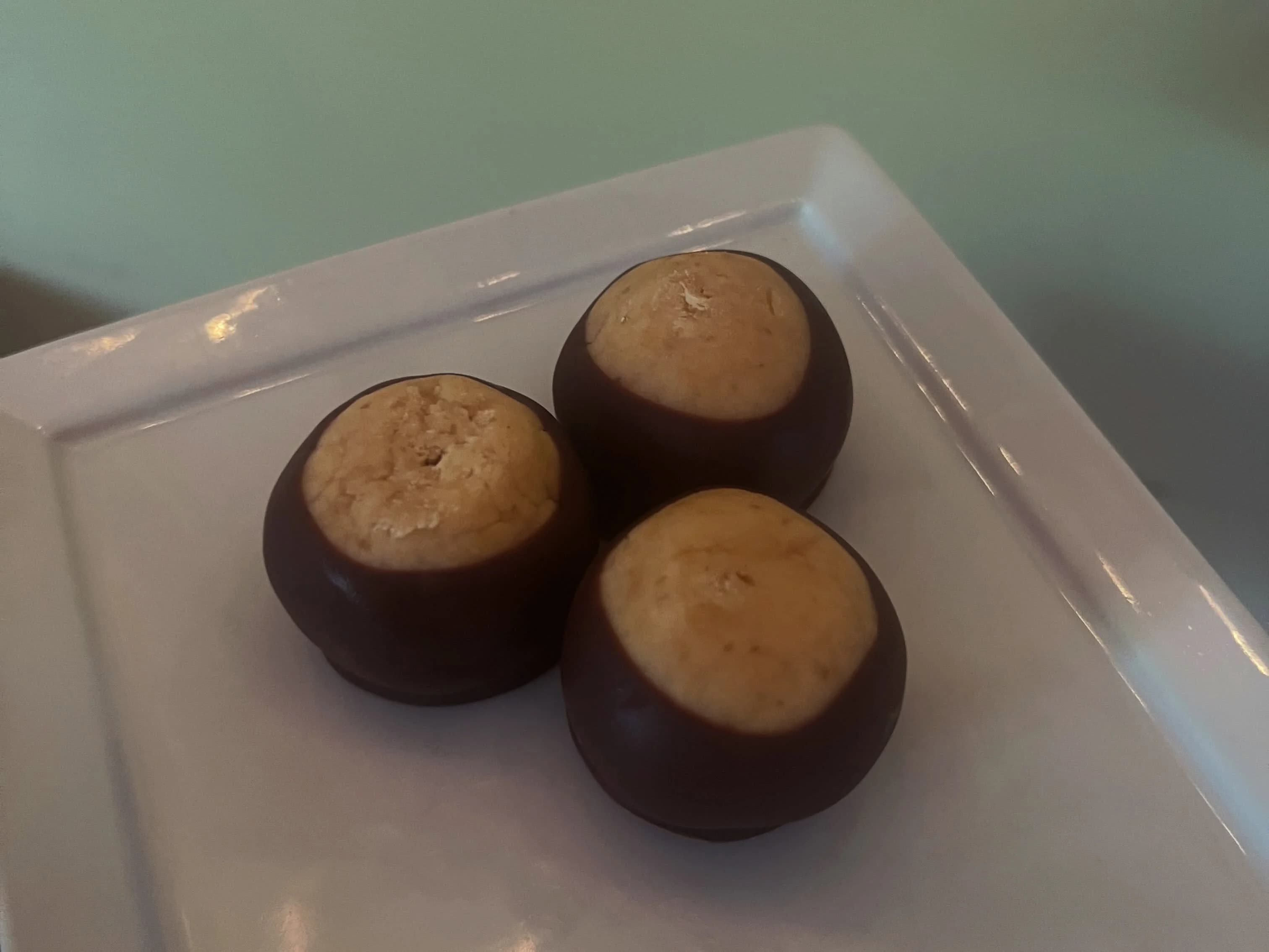 Three chocolate peanut butter Buckeyes on a plate