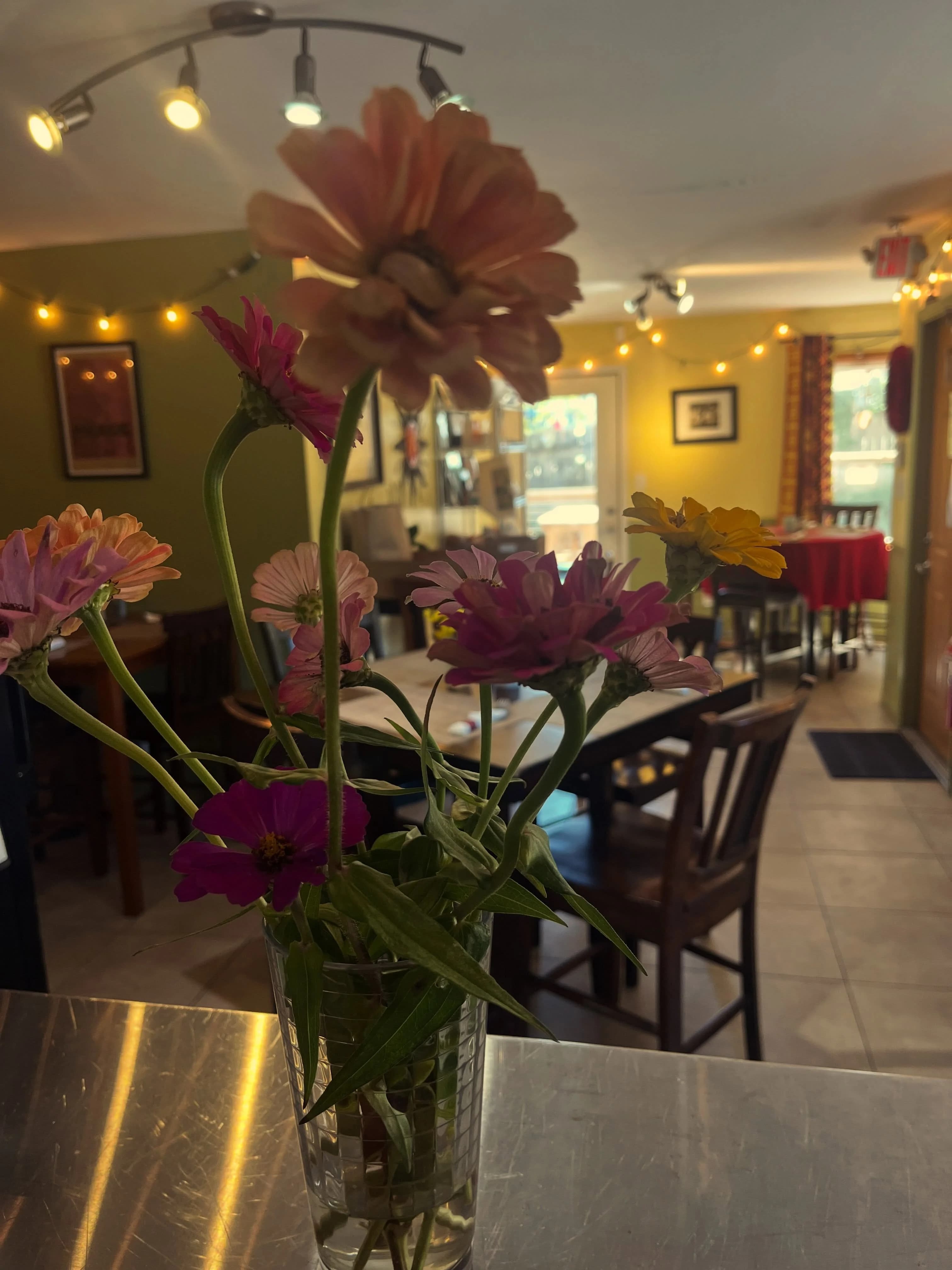 Pink flowers on a table inside Sun Belly’s yellow-walled dining room