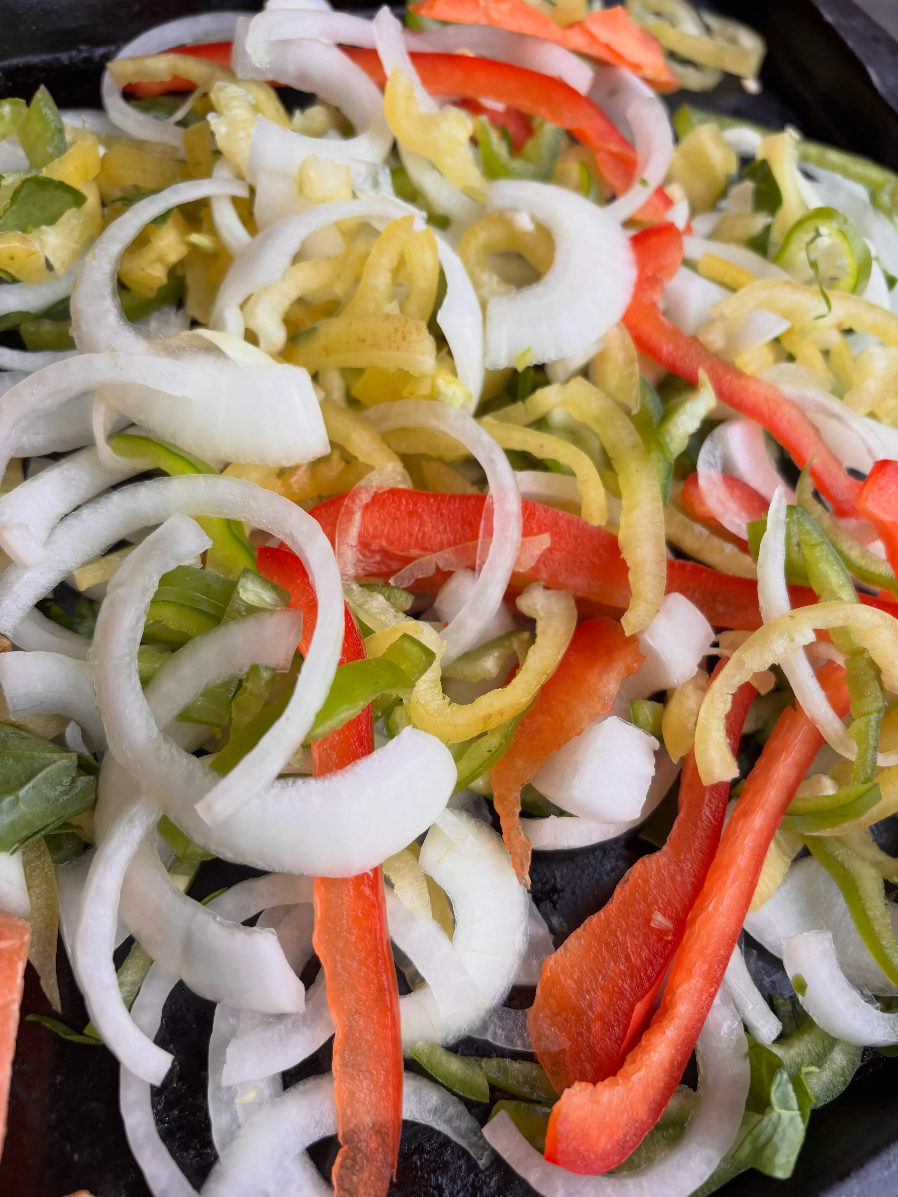 A generous tray of sliced peppers and onions being prepared for quesadillas